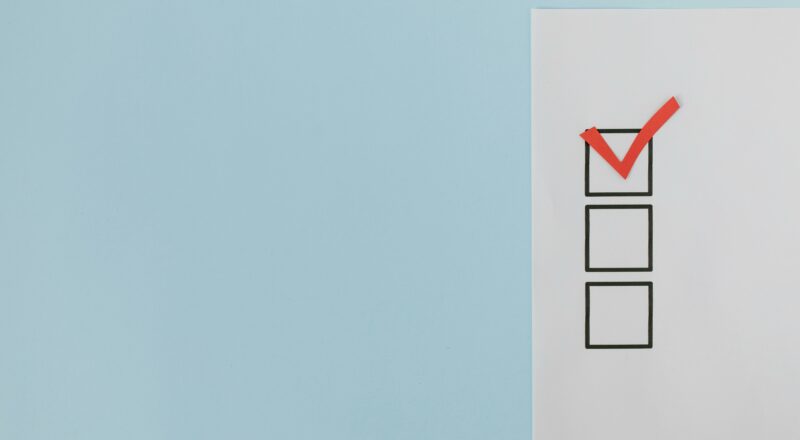 A minimalist checklist with a red checkmark on a blue background providing ample copy space